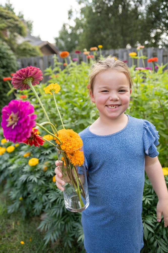 Josie in her garden holding a vase of flowers